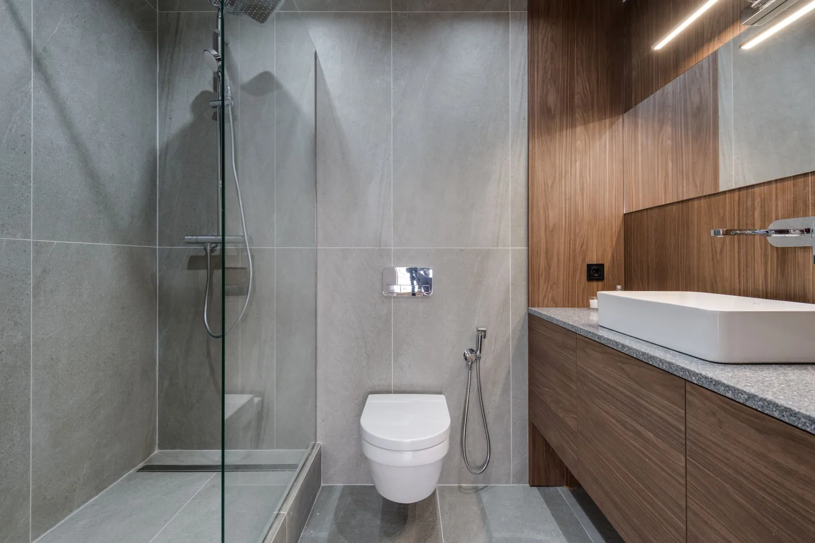 Gerenoveerde badkamer met inloopdouche, grote wandtegels en een zwevend wastafelmeubel