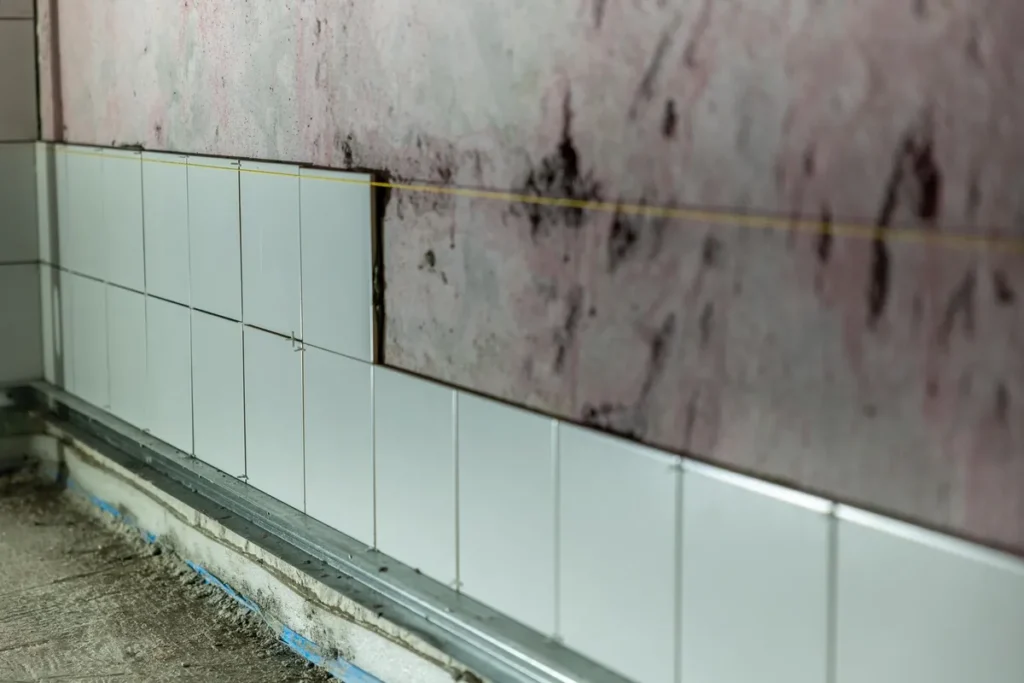 Badkamer tijdens de verbouwing met kale wanden, nieuwe leidingen en tegelwerk in uitvoering