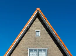 Kopgevel van een bakstenen woning met windveren langs het pannendak