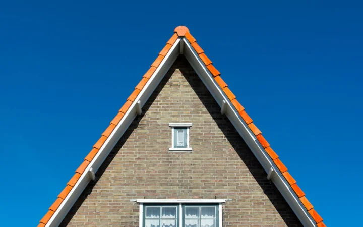 Kopgevel van een bakstenen woning met windveren langs het pannendak
